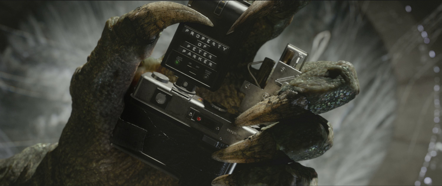Le Lézard, alias Curt Connors, incarné par Rhys Ifans, se saisissant de l'appareil photo de Peter Parker.....